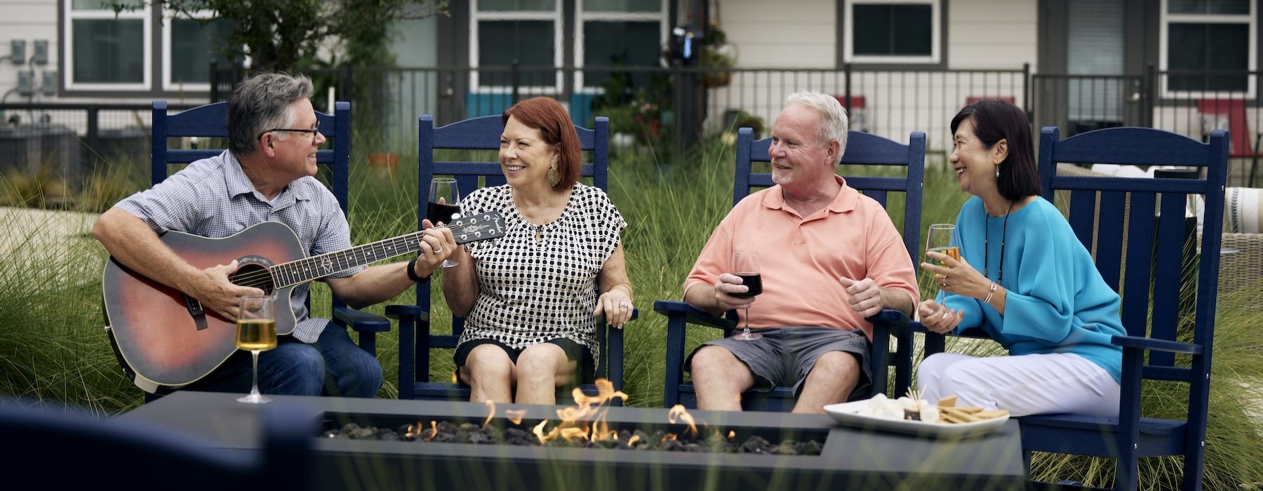 people sitting around fire and a man playing a guitar